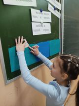 девочка вешает свой кораблик на доску